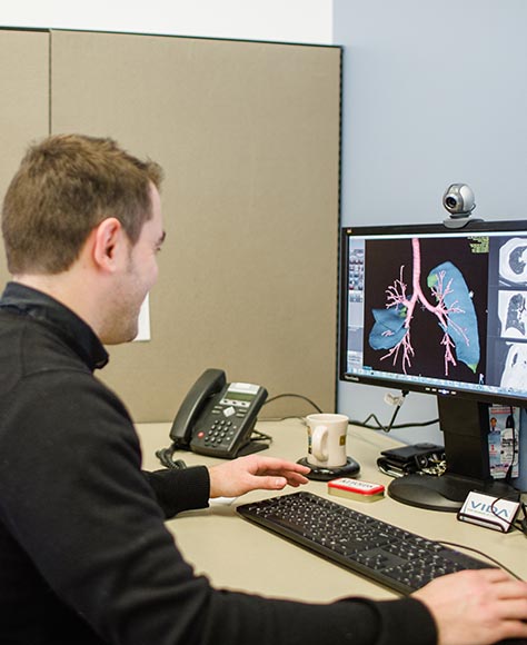 Man sitting at a desk at VIDA Diagnostics looking an image of the internal body.