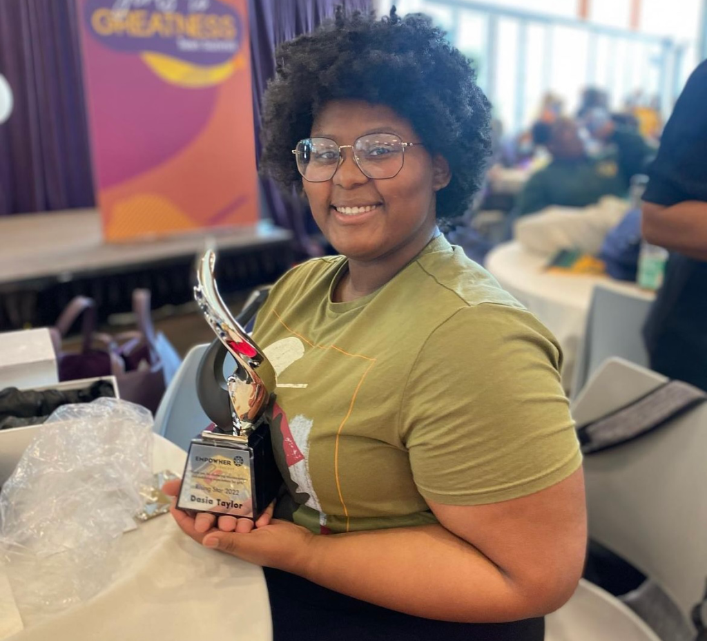 Dasia smiling at the camera and holding an award.