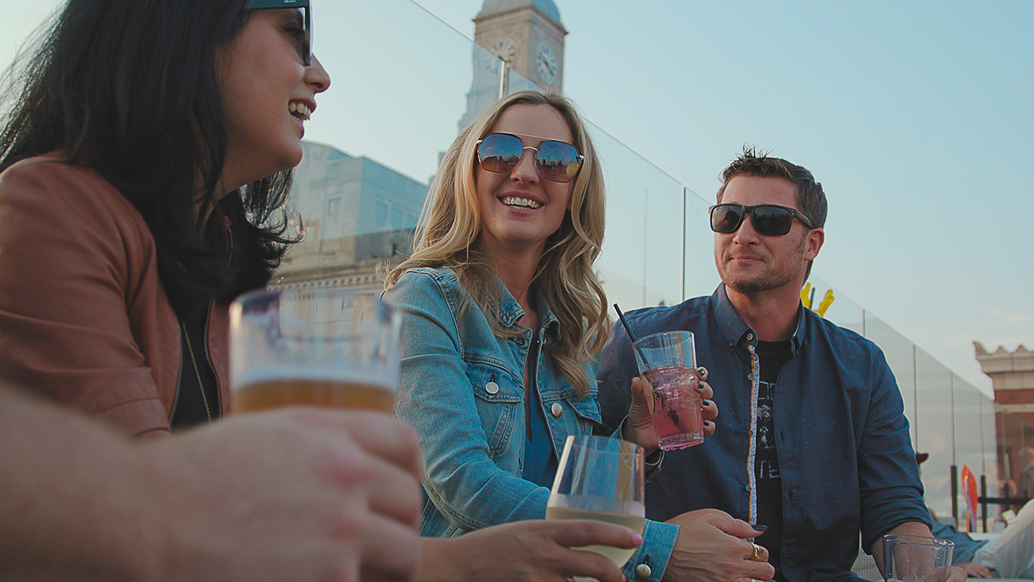 Three people wearing sunglasses and holding drives on a rooftop