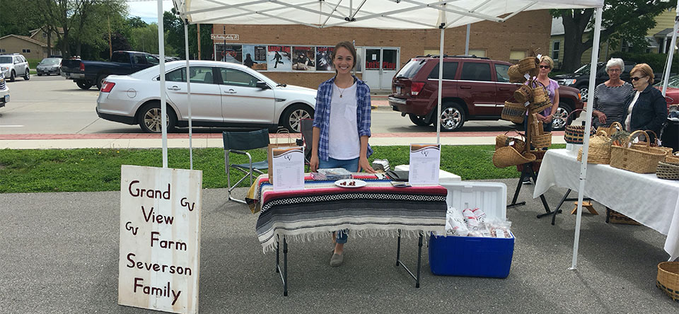 Amanda standing behind a table in her booth at her first farmer's market.