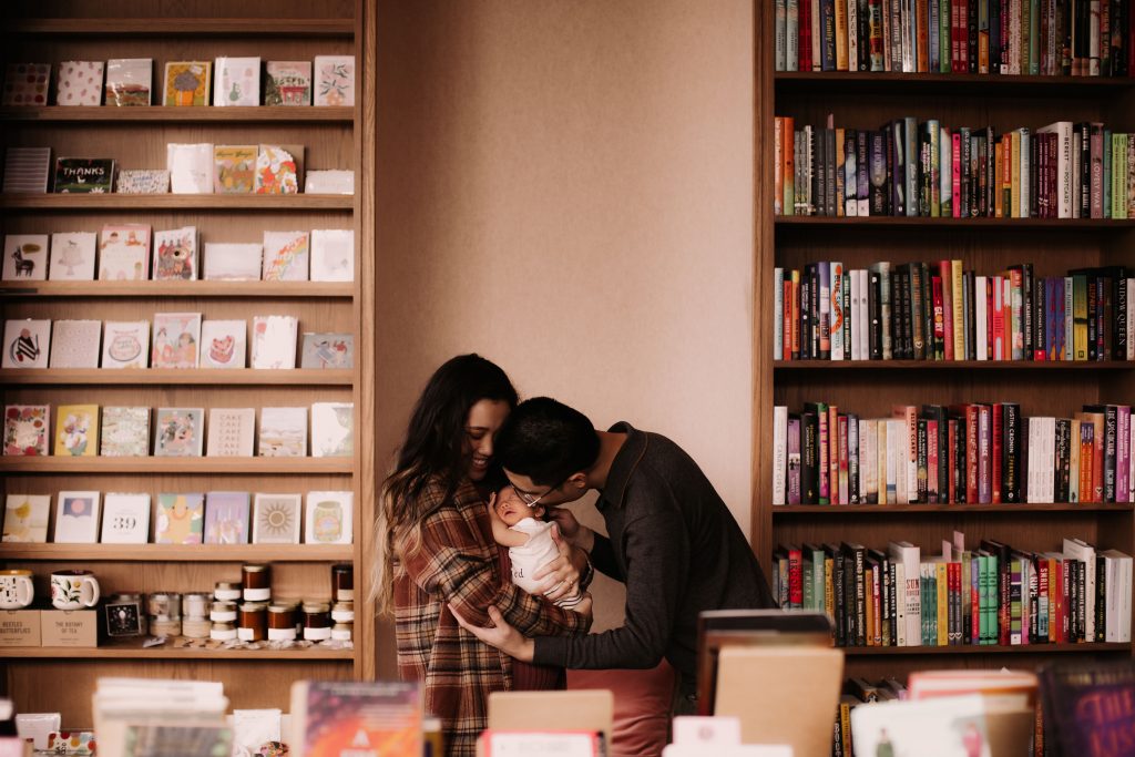 Linzi and Gooi standing in the bookstore holding their baby.