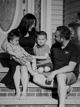 Family sitting outside a family home.