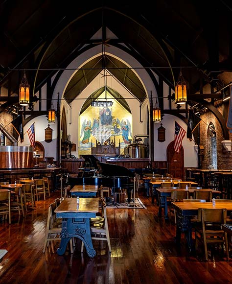 Inside view of the pews and stained glass windows of the Great Revivalist Brewery.