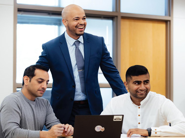 Three men together smiling at a person off camera.