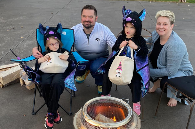 The Wells family outside with their daughter's in Halloween costumes.