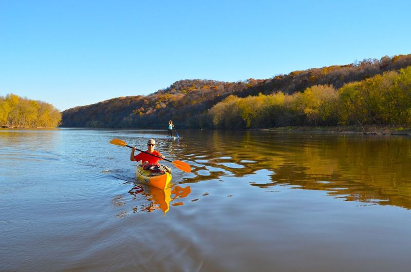kayaker and paddle boarder float down the mississippi river in dubuque iowa