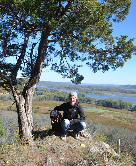 Man and dog on a hill outdoors at an Iowa park.
