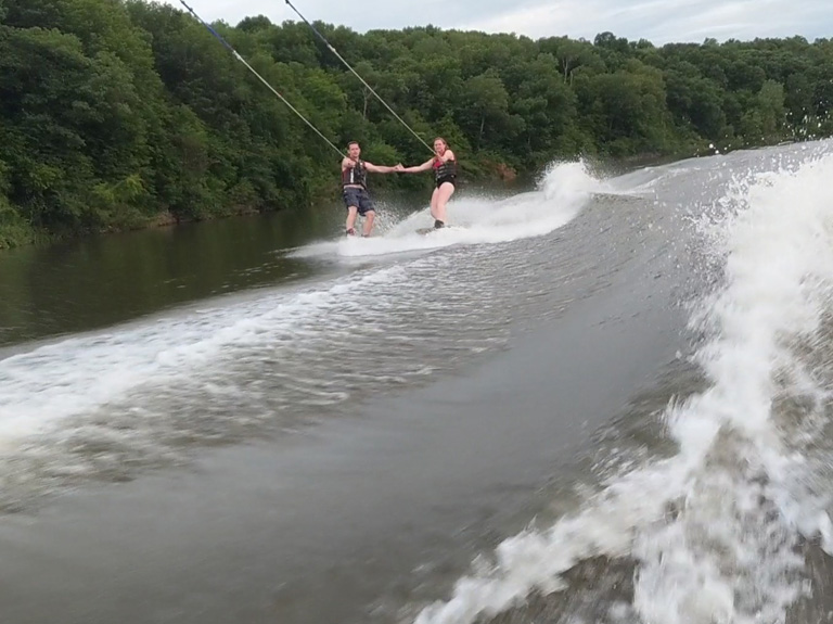 Two people tandem wake boarding on the river.