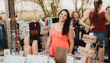 Woman standing at a sales table at a marketplace.