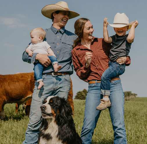 Amanda standing in a farm field with their two children.