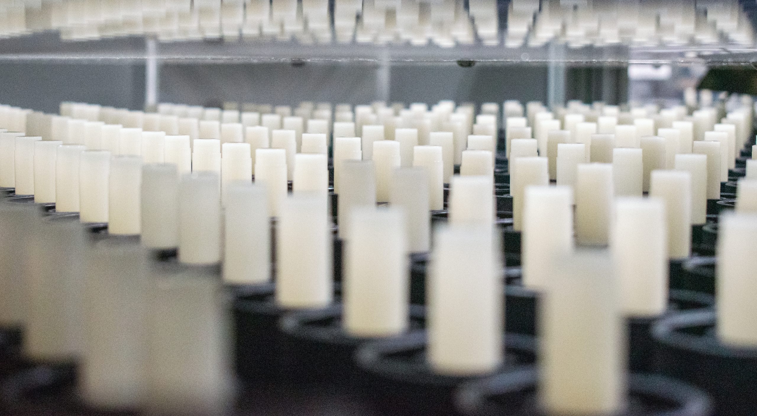 Rows of white lip balm tubes on a conveyer belt