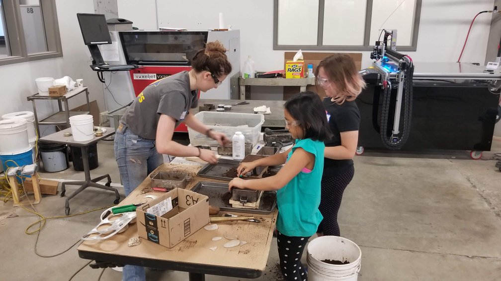 Woman and two young girls working on a project at a table.